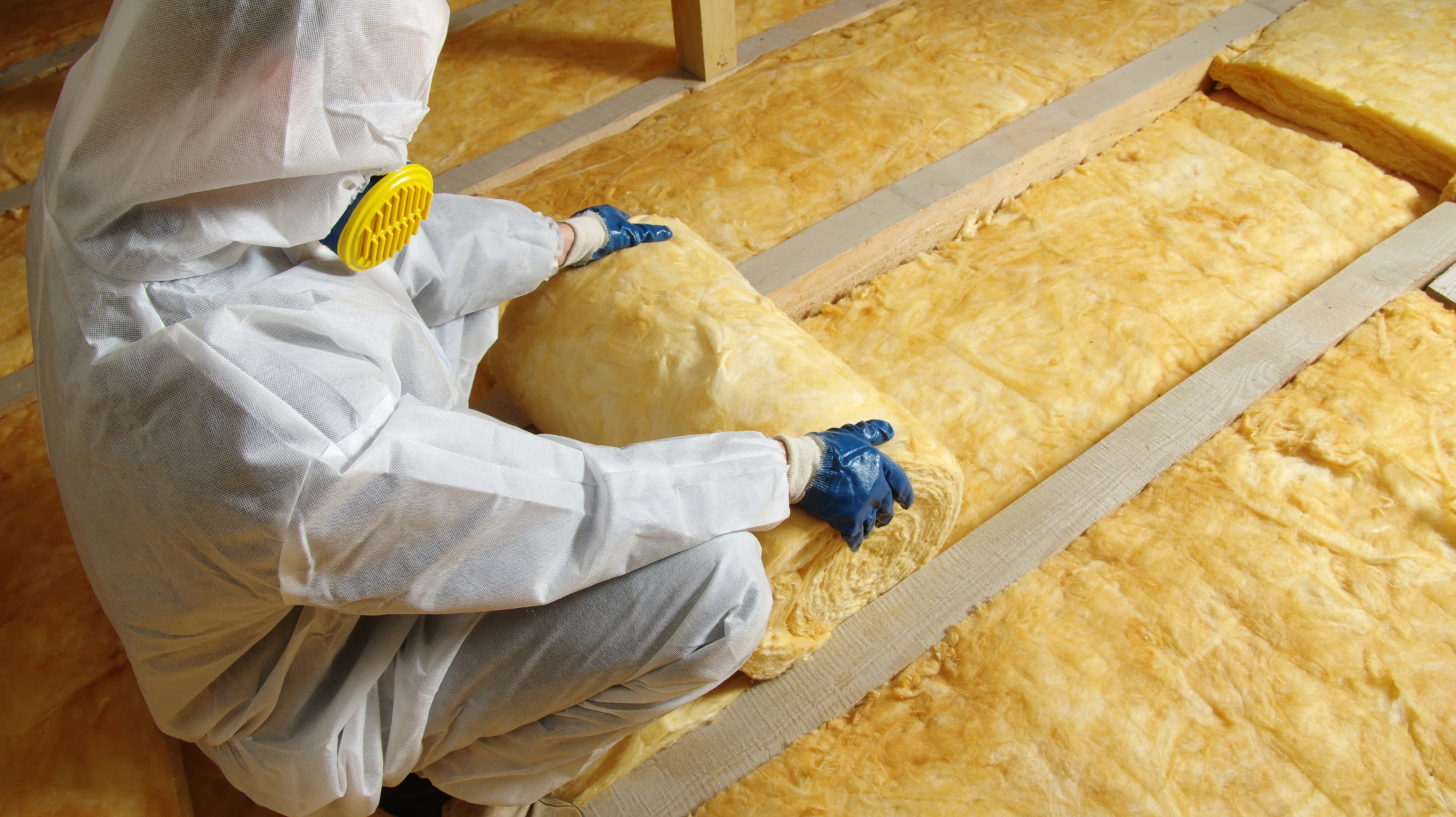 Combles d'une habitation avec charpente en bois apparente où s'effectue la projection d'isolant thermique par soufflage