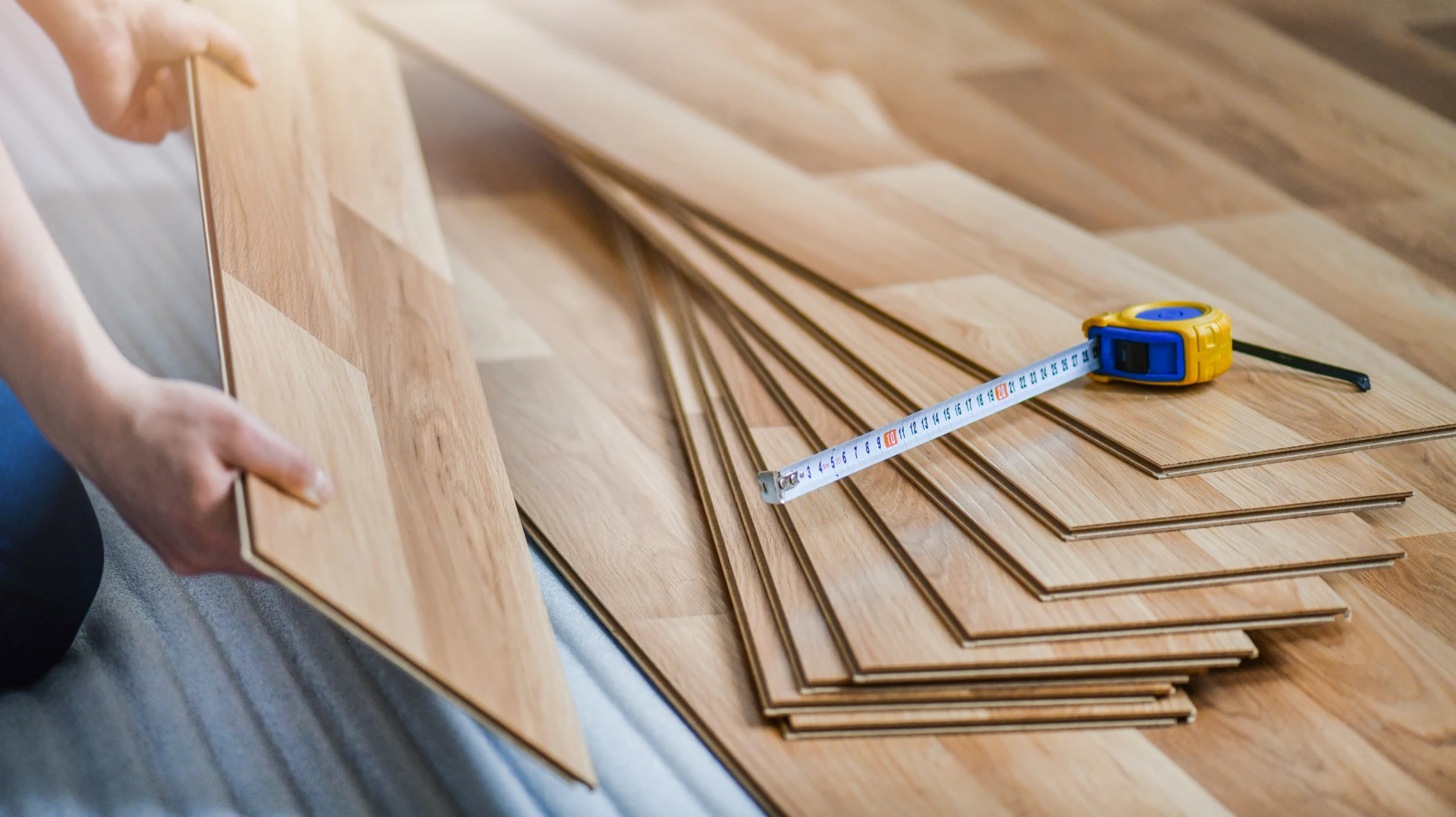 Gros plan professionnel montrant une main d'artisan en gant blanc appliquant du composé d'isolation ou de l'enduit de lissage sur une paroi intérieure avec une spatule large. Surface blanche ou gris clair en arrière-plan, texture de rénovation visible. Environnement d'intérieur en travaux, lumière naturelle ou professionnelle, mettant en avant la finition et la qualité des travaux de rénovation intérieure.