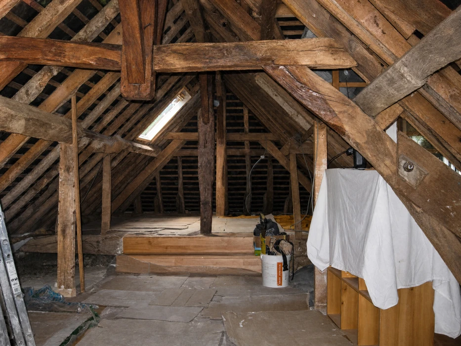 Ouvrier en tenue de travail installant des panneaux de placo sur mur intérieur, chantier de construction avec mur en briques apparentes